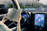 A passenger in an autonomous car reads a book while travelling