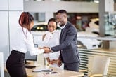 A car sale is completed with a handshake