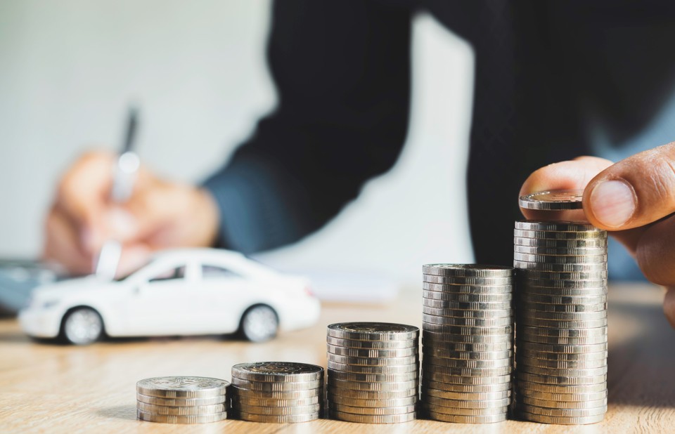 Men are putting coin and saint documents about cars with some coins calculator and car toy on desk.