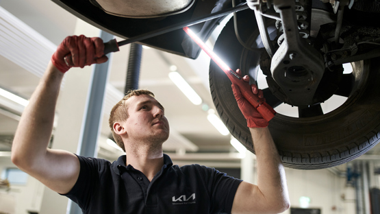 A Kia UK apprentice technician at work on a car