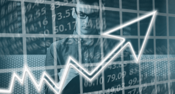 Man in glasses standing behind an arrow on a graph