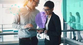 A businessman with a tablet talking to a businesswoman in an office