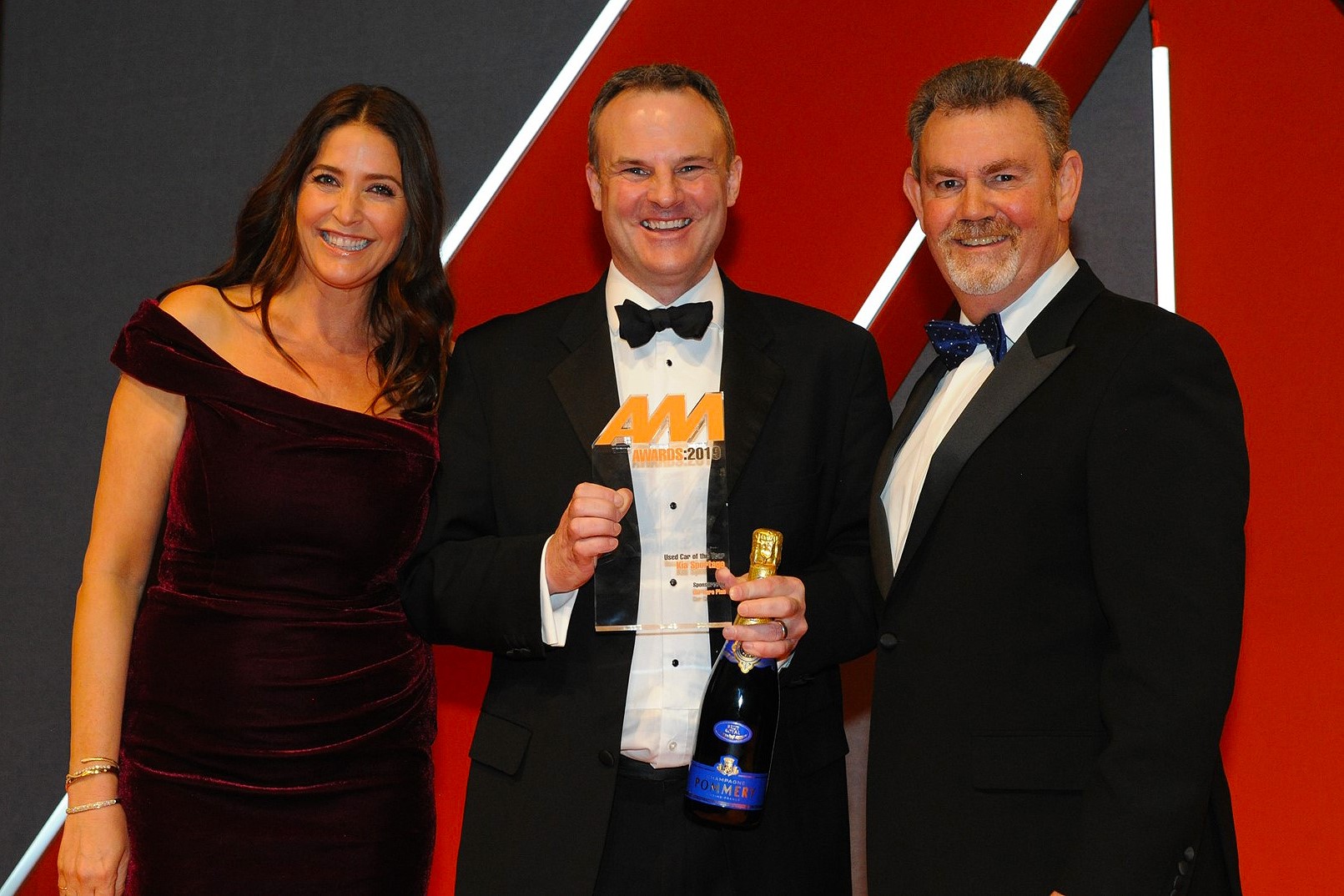 Simon Hetherington, commercial  director, Kia Motors (UK), accepts the  award from Philip Morrison, head of  corporate sales, Car Care Plan, right, and host Lisa Snowdon, left 