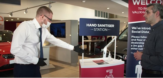 Vauxhall salesman with hand sanitiser for car buyer customer experience